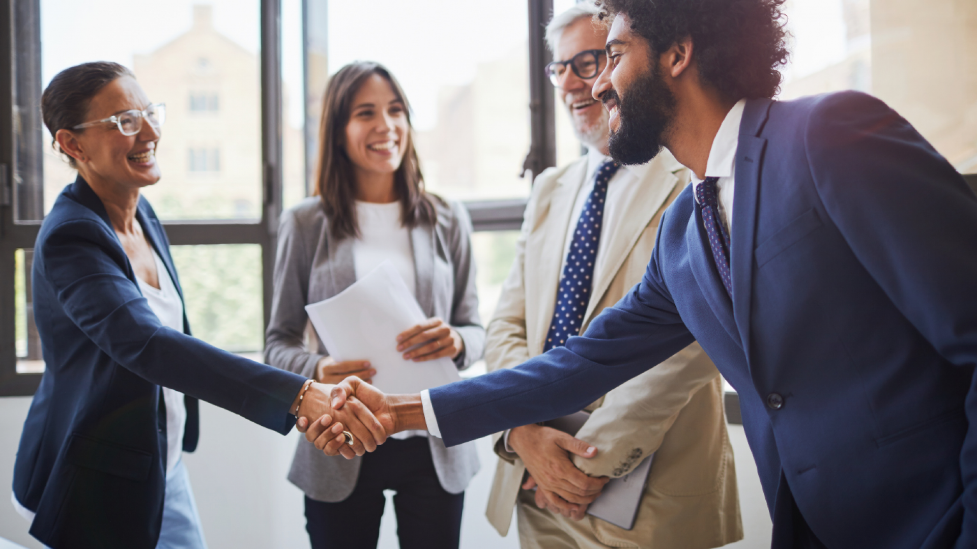 1. Business professionals shaking hands in a modern office setting, symbolizing partnership and collaboration.